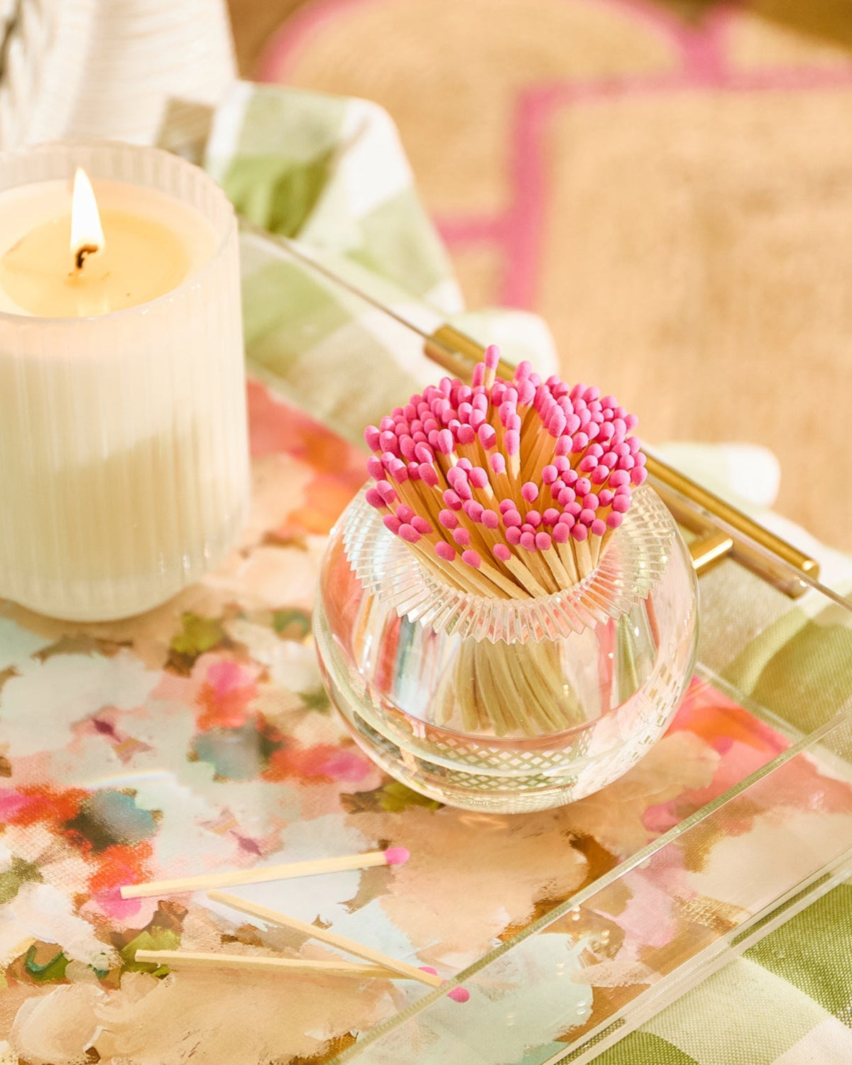 Decorative tray with a candle, matches, and decorative items on a checkered tablecloth.